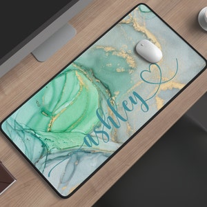 May include: A teal green and gold marble design mousepad with the name "ashley" written in teal blue cursive script and a heart symbol.