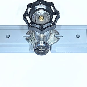 May include: A silver water shut-off valve with a black handle, mounted on a grey plastic wall plate. The valve has a label that reads "Lead Free" and "Made in India".