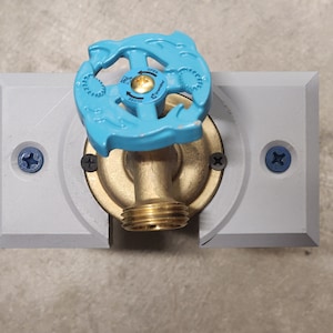 May include: An outdoor water tap with a blue and gold lever handle. The tap is mounted on a grey plastic wall plate with two screws.