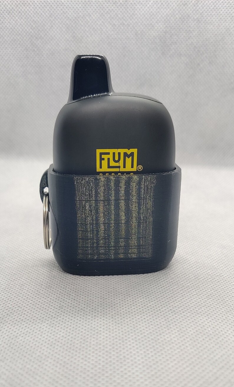 May include: Black and yellow FLUM disposable vape device case with a textured black silicone cover and a silver key ring.
