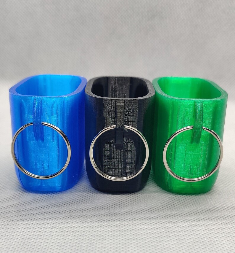 May include: Three 3D printed keychains, one blue, one black, and one green, each with a silver ring.