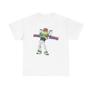 Pode incluir: Camiseta branca com uma imagem de desenho animado do Buzz Lightyear do Toy Story, usando um boné de beisebol vermelho e óculos de sol. O personagem é verde, branco e roxo.