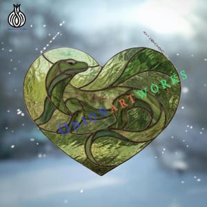 May include: A heart-shaped stained glass artwork with a green serpent design. The piece is made of various shades of green glass and is suspended by a chain. The text "ONION ART WORKS" is visible.