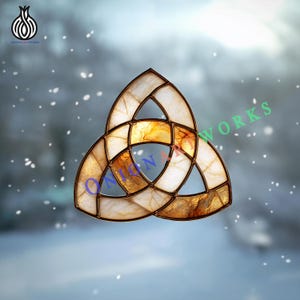 May include: A stained glass Celtic knot, triangular in form, with a brown frame and a blend of white and amber glass. The design is set against a blurred, snowy backdrop. The text "ONION ARTWORKS" is visible.