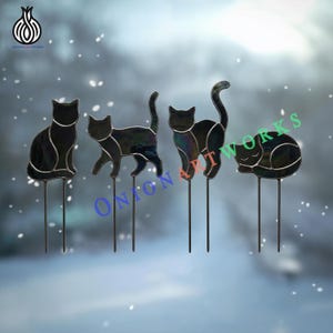 May include: Four black stained glass cat silhouettes mounted on thin metal stakes. The cats are depicted in different poses: sitting, walking, standing with a raised tail, and curled up sleeping. Each figure features dark, iridescent glass panels.