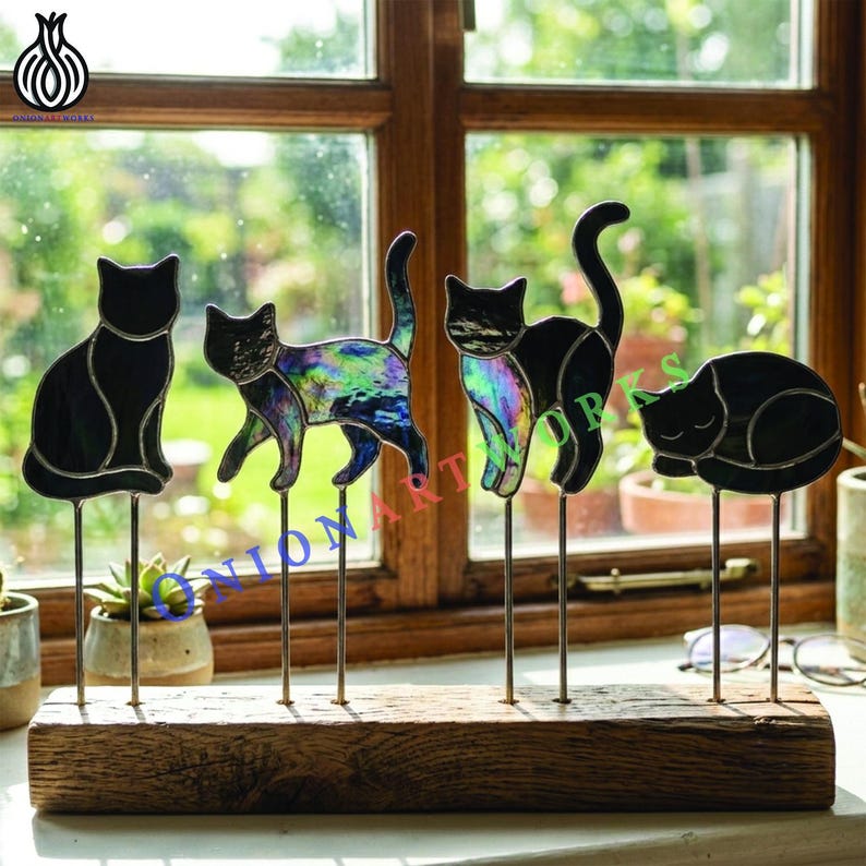 May include: Four stained glass cat silhouettes mounted on thin metal rods inserted into a rectangular wooden base. Two cats are solid black, while two feature iridescent, multi-colored glass panels. The cats are in various poses.
