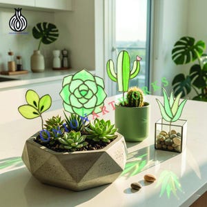 Puede incluir: Una jardinera geométrica de hormigón llena de suculentas, junto a cactus decorativos de cristal y obras de arte de suculentas. Un pequeño cactus verde está en una maceta verde. La escena está ambientada en una encimera blanca con luz natural.