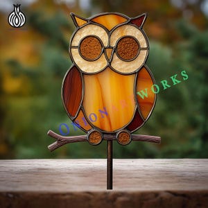 May include: Stained glass owl yard art in shades of amber, brown, and cream. The owl is perched on a branch attached to a metal stake. The artwork features the text "ONION ART WORKS".