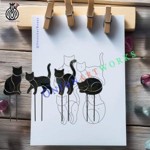 May include: Four black stained glass cat figures with metal stakes, displayed alongside a white paper pattern sheet featuring outlines of cats. The glass cats are in various poses, including sitting, walking, and sleeping, with visible solder lines.