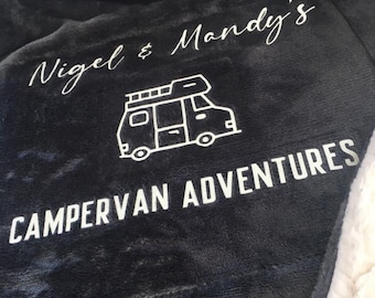 May include: A black and white campervan graphic on a dark gray fleece blanket with the text "Nigel & Mandy's Campervan Adventures".