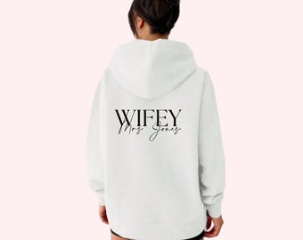 May include: White hoodie with the text "WIFEY Mrs. Jones" printed on the back.