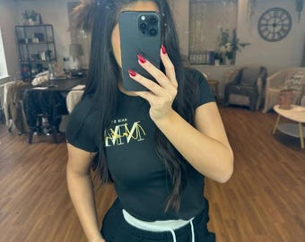 May include: A black t-shirt with a gold graphic that says "MM" and a white drawstring jogger.
