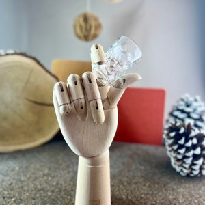 Peut inclure: Un mod&egrave;le de main en bois tenant un verre &agrave; shot en verre transparent avec un motif textur&eacute;.