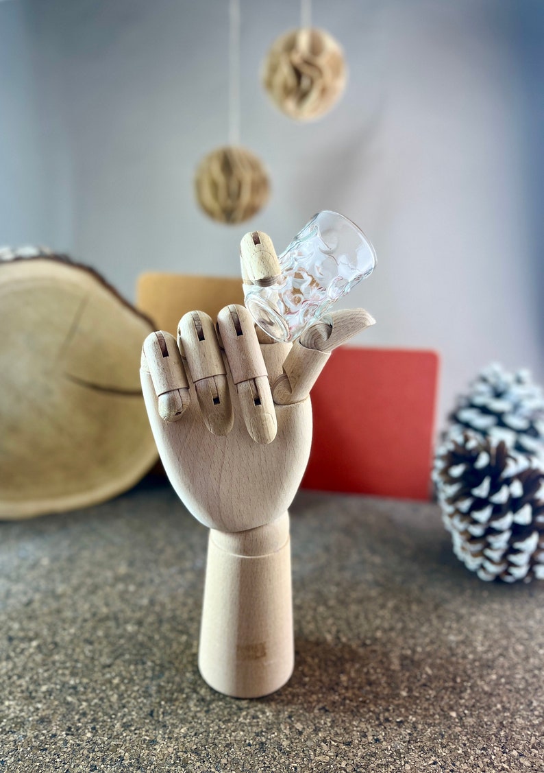 Peut inclure: Un mod&egrave;le de main en bois tenant un verre &agrave; shot en verre transparent avec un motif textur&eacute;.