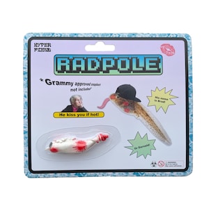 May include: A plastic toy package with a cartoon image of a tadpole wearing a hat. The package says "Radpole" and "His name is Brad!" The toy is a small, white tadpole with red spots. The package also says "He kiss you if hot!" and "Or Darnald!"