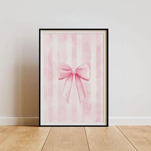 Puede incluir: Un lazo rosa de acuarela sobre un fondo a rayas rosa y blanco. El lazo está atado en un nudo y los extremos fluyen.