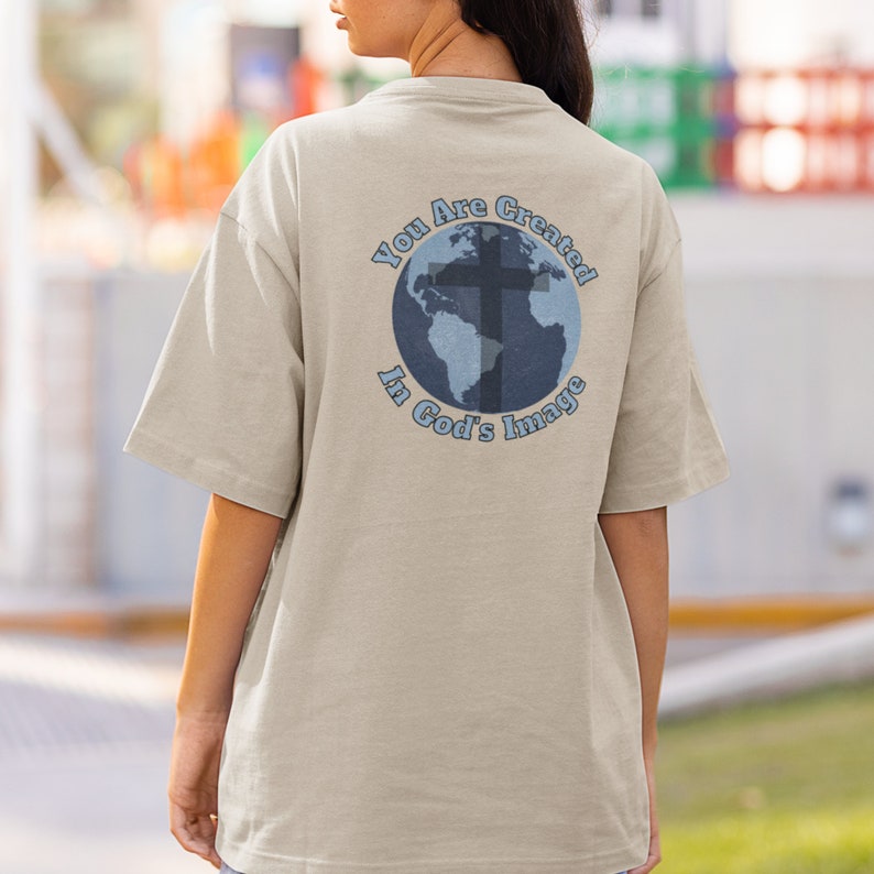 May include: A beige t-shirt with a blue and white graphic of a globe with a cross on it. The text "You Are Created In God's Image" surrounds the globe.