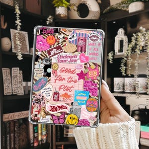 May include: A clear tablet case covered in a collage of colorful stickers, including text like 'Good for the Plot', 'Unclench Your Jaw', 'Hot Mess', and 'What if it all works out?', alongside various illustrations of Dr. Pepper cans, smiley faces, and animals.