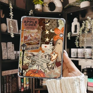 May include: A clear tablet case featuring a collage of autumn-themed imagery including a pumpkin, a ghost, a street lamp, stars, and text that reads Delicious Apple Cider Snohomish Washington and Annual Autumn Festival Mars Hollow.