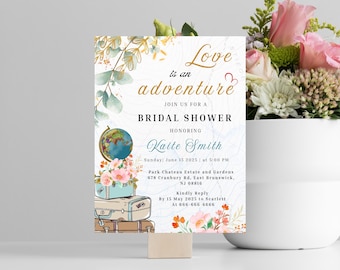 Puede incluir: Una invitación a una despedida de soltera con un fondo de acuarela que presenta un globo terráqueo, maletas y detalles florales. El texto dice "El amor es una aventura" e incluye el nombre de la novia, la fecha, la hora y el lugar.