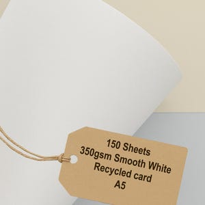 May include: White A5 recycled card stock with a brown tag attached. The tag reads "150 Sheets, 350gsm Smooth White Recycled card". The FSC logo is in the upper right corner, and the BuyEco logo is in the lower right.