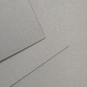 K&ouml;nnte beinhalten: Nahaufnahme eines Stapels grauen Conqueror Laid Cartridge Papiers, 300 g/m&sup2;. Das Papier hat eine strukturierte Oberfl&auml;che und ist ideal zum Drucken und Basteln.