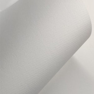 K&ouml;nnte beinhalten: Nahaufnahme eines wei&szlig;en, strukturierten Papierblattes. Das Papier ist mit "Conqueror Laid Milk White 100gsm" beschriftet und tr&auml;gt das Jampak-Logo unten rechts.