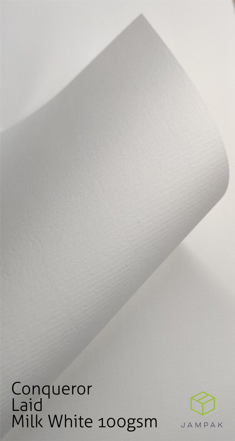 K&ouml;nnte beinhalten: Nahaufnahme eines wei&szlig;en, strukturierten Papierblattes. Das Papier ist mit "Conqueror Laid Milk White 100gsm" beschriftet und tr&auml;gt das Jampak-Logo unten rechts.