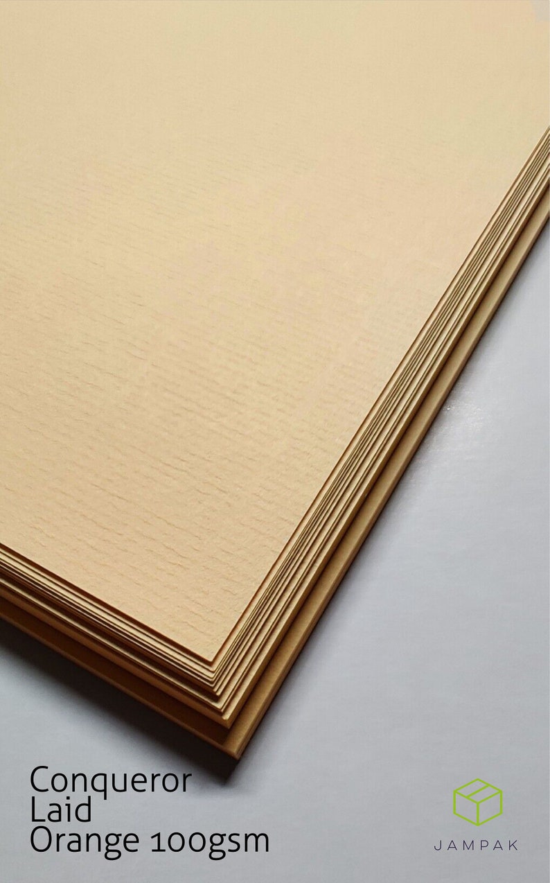 K&ouml;nnte beinhalten: Ein Stapel Conqueror Laid Orange Papier, 100 g/m&sup2;. Das Papier ist hellorange und hat eine leicht strukturierte Oberfl&auml;che.