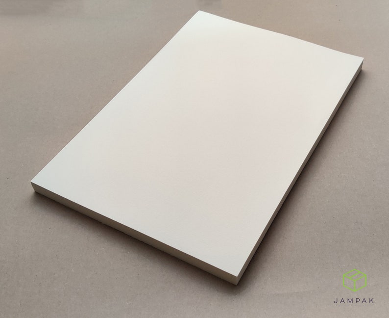 K&ouml;nnte beinhalten: Ein leeres, cremefarbenes Blatt Papier. Das Papier ist glatt und hat einen leichten Glanz.