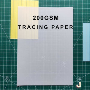 May include: A sheet of 200GSM tracing paper on a green cutting mat. The paper is translucent and has a grid pattern.
