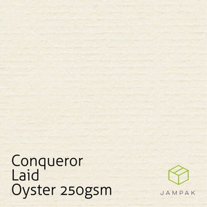 K&ouml;nnte beinhalten: Nahaufnahme eines wei&szlig;en, strukturierten Papiers mit dem Text "Conqueror Laid Oyster 250gsm" und einer kleinen braunen Schachtel mit dem Text "JAMPAK" in Wei&szlig;.