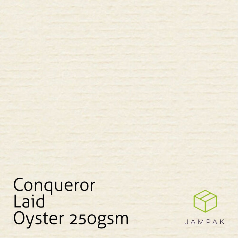 K&ouml;nnte beinhalten: Nahaufnahme eines wei&szlig;en, strukturierten Papiers mit dem Text "Conqueror Laid Oyster 250gsm" und einer kleinen braunen Schachtel mit dem Text "JAMPAK" in Wei&szlig;.