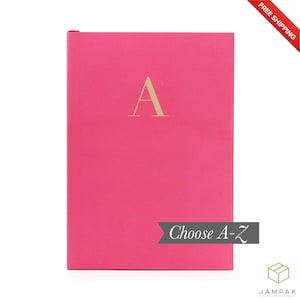 May include: A bright pink notebook with a gold letter "A" on the front. The notebook has the text "Choose A-Z" on the bottom right corner.