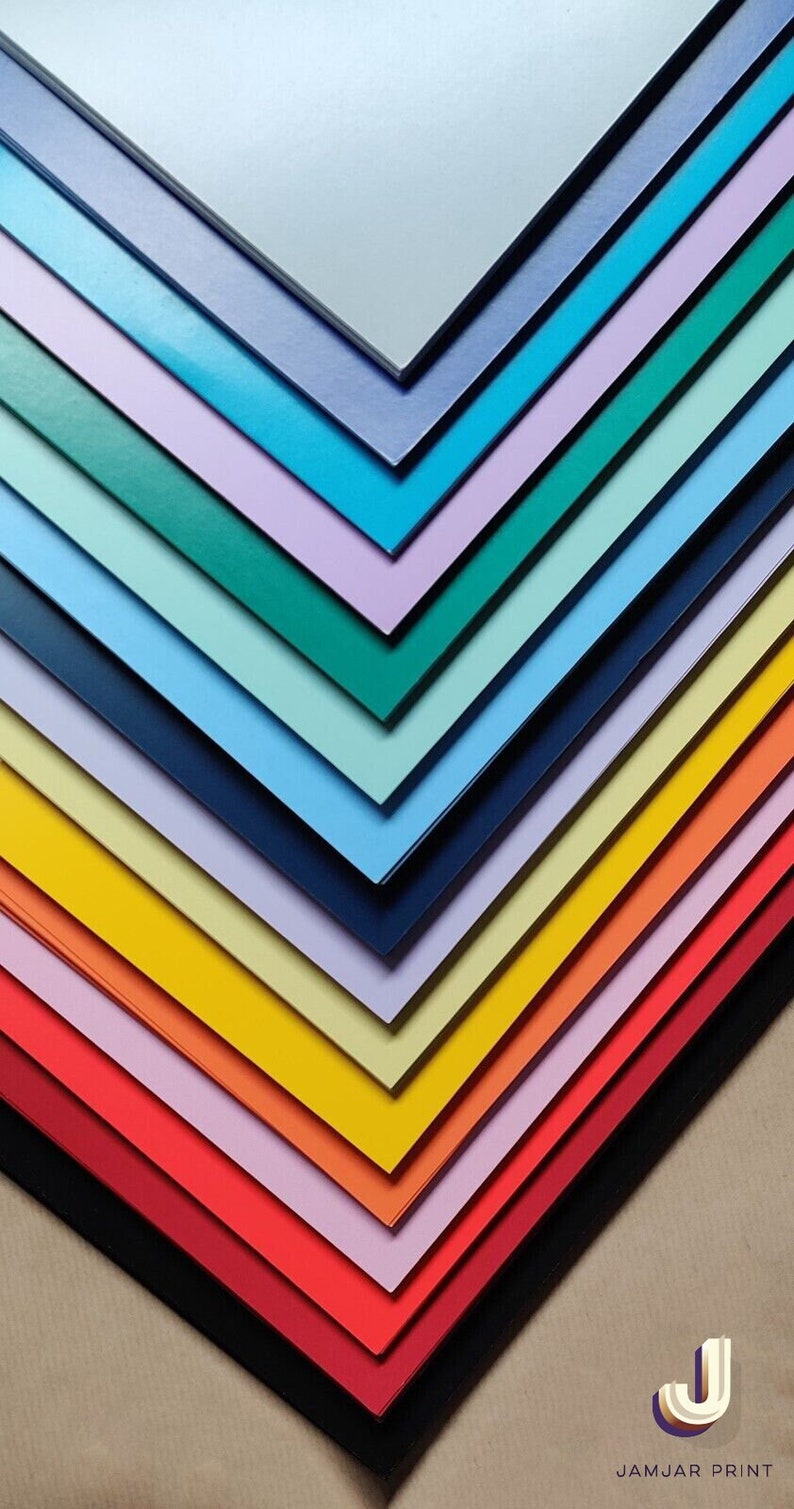 Puede incluir: Una pila de cartulina de colores en varios tonos de azul, verde, amarillo, naranja, rojo y rosa. El papel est&aacute; dispuesto en forma de abanico, con la hoja superior de color azul claro y la hoja inferior de color negro. El papel est&aacute; sobre una superficie marr&oacute;n. JAMJAR PRINT est&aacute; impreso en blanco sobre fondo negro.