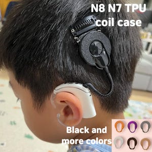 Puede incluir: Primer plano de la cabeza de una persona con un audífono en blanco y negro. El texto "N8 N7 TPU coil case" es visible. Se muestran opciones de color adicionales con el texto "Black and more colors".
