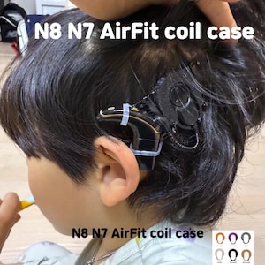以下が含まれることがあります： 人の頭に取り付けられた黒と金のN8 N7 AirFitコイルケース。ケースは透明なプラスチッククリップで固定されています。「N8 N7 AirFit coil case」というテキストが白で表示されています。コイルケースのカラーチャートが表示されています。