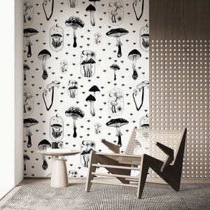 May include: Black and white mushroom illustration wallpaper with a repeating pattern of mushrooms, moons, and stars. The wallpaper is on a white background and is shown in a room with a wooden chair and a side table.