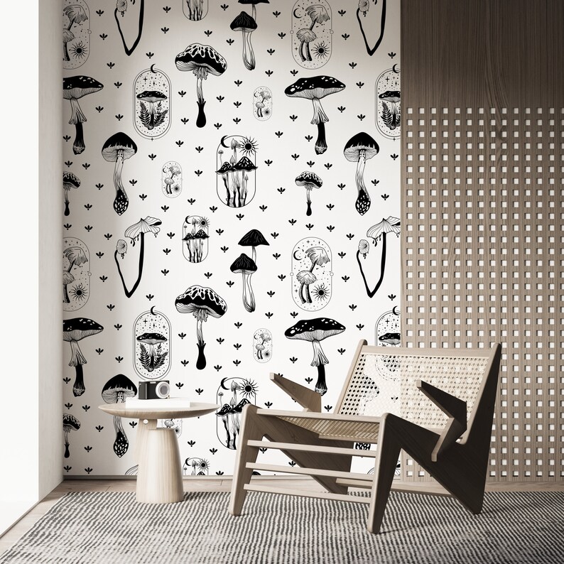 May include: Black and white mushroom illustration wallpaper with a repeating pattern of mushrooms, moons, and stars. The wallpaper is on a white background and is shown in a room with a wooden chair and a side table.
