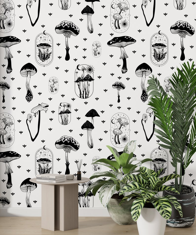 May include: Black and white wallpaper featuring a repeating pattern of mushrooms and celestial elements. The wallpaper is shown on a wall with a small table and two potted plants.