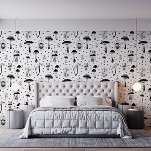 May include: A white bedroom with a black and white mushroom patterned wallpaper. A white bed with a white duvet and two white pillows is in the centre of the room. There are two small black bedside tables with white lamps on either side of the bed.