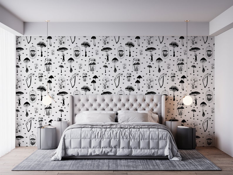 May include: A white bedroom with a black and white mushroom patterned wallpaper. A white bed with a white duvet and two white pillows is in the centre of the room. There are two small black bedside tables with white lamps on either side of the bed.
