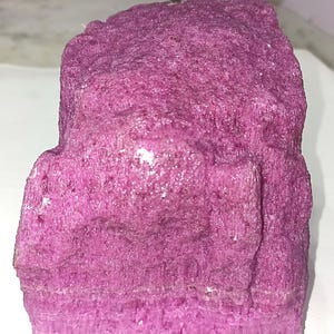 May include: A large, irregularly shaped piece of pink selenite crystal. The crystal has a rough, textured surface and a layered appearance.