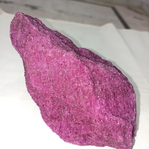 May include: A large, rough, pink rock with a textured surface.