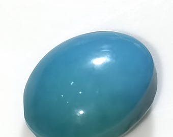 May include: An oval soap bar with a smooth surface, displaying a gradient of blue and teal colours. The soap has a glossy finish and is set against a white background. The shape resembles a large gemstone.
