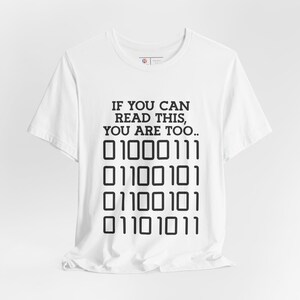 May include: White t-shirt with the text "IF YOU CAN READ THIS, YOU ARE TOO..." and a series of binary code: "01000111 01100101 01100101 01101011"