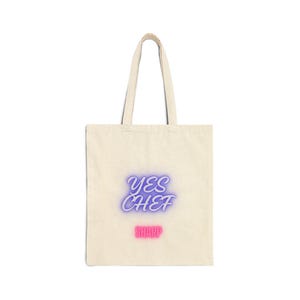 Puede incluir: Bolso tote de color crema con las palabras "YES CHEF" en letras de neón azules y moradas, y la palabra "SHARP" en rosa. El bolso tiene dos asas y está hecho de un material similar a la lona.