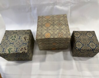 Chinese silk nesting boxes; three boxes with tan silk and blue lining