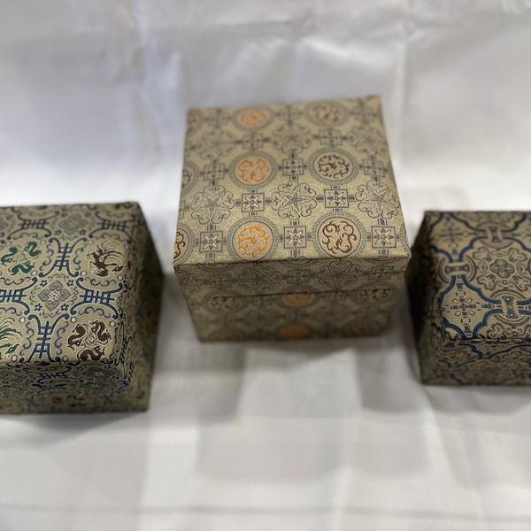 Chinese silk nesting boxes; three boxes with tan silk and blue lining