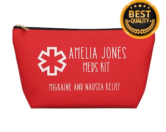 Può includere: Un astuccio rosso con cerniera con la scritta "AMELIA JONES MEDS KIT" e "MIGRAINE AND NAUSEA RELIEF" in bianco. Un simbolo medico bianco è a sinistra. Un sigillo "BEST QUALITY" dorato e nero è in alto a destra.